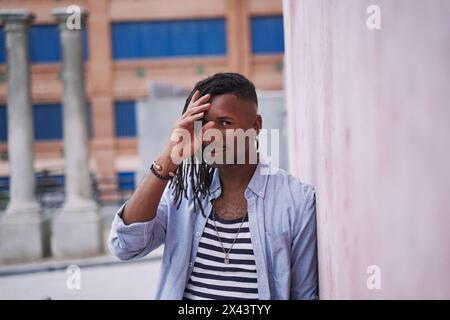 Porträt eines stilvollen jungen Mannes, der in die Kamera mit Dreadlocks und einer Baskenmütze blickt Stockfoto