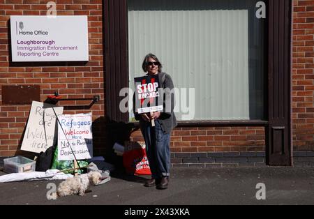 Loughborough, Leicestershire, Großbritannien. 30. April 2024. Ein Demonstrant, der gegen die geplante Deportation von Migranten und Flüchtlingen nach Ruanda demonstriert, steht vor einem Meldezentrum für Einwanderungsbehörden. Credit Darren Staples/Alamy Live News. Stockfoto