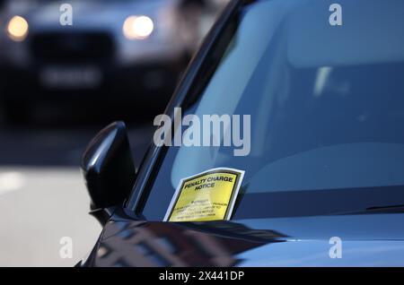 Loughborough, Leicestershire, Großbritannien. 30. April 2024. Ein Hinweis auf eine Strafgebühr, der an der Windschutzscheibe eines Autos hängt, das auf gelben Doppellinien geparkt ist. Stockfoto