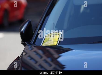 Loughborough, Leicestershire, Großbritannien. 30. April 2024. Ein Hinweis auf eine Strafgebühr, der an der Windschutzscheibe eines Autos hängt, das auf gelben Doppellinien geparkt ist. Stockfoto