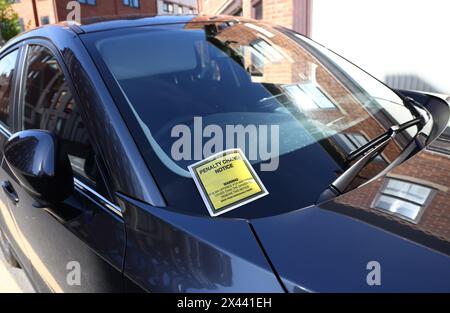 Loughborough, Leicestershire, Großbritannien. 30. April 2024. Ein Hinweis auf eine Strafgebühr, der an der Windschutzscheibe eines Autos hängt, das auf gelben Doppellinien geparkt ist. Stockfoto