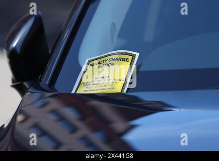 Loughborough, Leicestershire, Großbritannien. 30. April 2024. Ein Hinweis auf eine Strafgebühr, der an der Windschutzscheibe eines Autos hängt, das auf gelben Doppellinien geparkt ist. Stockfoto