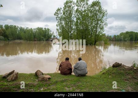 Srinagar, Indien. April 2024 30. Männer sitzen am Ufer des Flusses Jhelum, als der Wasserstand im Fluss am Dienstagmorgen die „Hochwasserdeklaration“-Markierung in Srinagar überschritt. In Jammu und Kaschmir wird erwartet, dass sich das Wetter ab morgen verbessern wird, wobei die örtliche Wetterabteilung bis zum 5. Mai allgemein bewölkte Bedingungen vorhersagt. Quelle: SOPA Images Limited/Alamy Live News Stockfoto