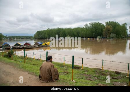 Srinagar, Indien. April 2024 30. Ein Mann sitzt am Ufer des Flusses Jhelum, als der Wasserstand des Flusses am Dienstagmorgen in Srinagar die „Hochwasserdeklaration“-Markierung überschritt. In Jammu und Kaschmir wird erwartet, dass sich das Wetter ab morgen verbessern wird, wobei die örtliche Wetterabteilung bis zum 5. Mai allgemein bewölkte Bedingungen vorhersagt. Quelle: SOPA Images Limited/Alamy Live News Stockfoto