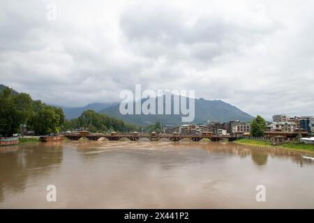 Srinagar, Indien. April 2024 30. Man sieht Menschen, die über eine Brücke laufen, während der Wasserstand im Jhelum am Dienstagmorgen die „Hochwasserdeklaration“-Markierung in Srinagar überquerte. In Jammu und Kaschmir wird erwartet, dass sich das Wetter ab morgen verbessern wird, wobei die örtliche Wetterabteilung bis zum 5. Mai allgemein bewölkte Bedingungen vorhersagt. (Foto: Faisal Bashir/SOPA Images/SIPA USA) Credit: SIPA USA/Alamy Live News Stockfoto