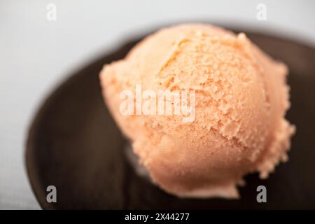 Ein frischer Löffel hausgemachtes Erdbeereis in einer schwarzen Schüssel Stockfoto