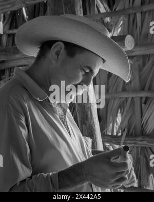 Ein Infrarotbild eines Tabakbauers, der in einer der Trockenställen auf Benito’s Tobacco Farm in Vinales, Kuba, eine Zigarre raucht. Stockfoto