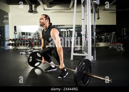Ein fokussierter Mann in aktiver Kleidung führt eine Hocke mit einer Langhantel in einem Fitnessstudio aus und zeigt seine Stärke und Entschlossenheit. Stockfoto