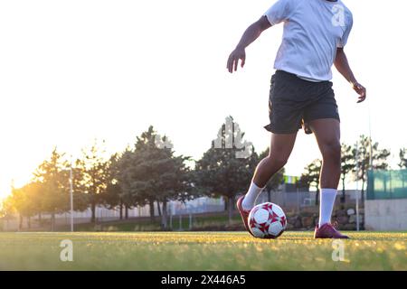 Fußballspieler auf dem Spielfeld, der mit dem Ball läuft. Nahaufnahme der Füße des Spielers, die mit dem Ball auf dem Spielfeld laufen. Spielerfüße mit dem Ball, der A erzielt Stockfoto