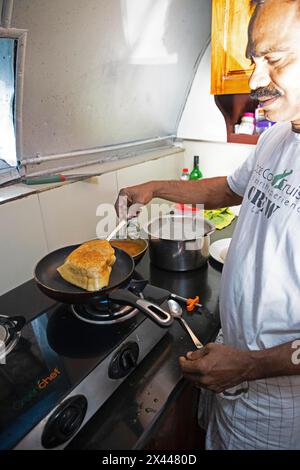 Indischer Mann, der Dosa oder Pfannkuchen in einer Schiffsküche frittiert, traditionelles Kerala-Gericht, Kerala, Indien Stockfoto