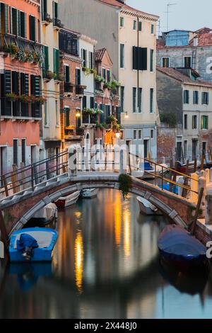 Vertäute Boote und Fußgängerbrücke über den Rio de la Toletta Kanal mit alten architektonischen Wohnhäusern in der Abenddämmerung, Dorsoduro Viertel, Venedig Stockfoto