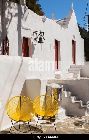 Zwei gelbe, modern gestaltete Stühle vor dem Gebäude mit kleiner Kapelle, Mykonos-Stadt, Mykonos-Insel, Griechenland Stockfoto