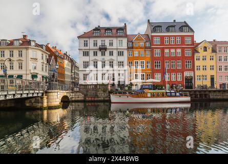 Kanalbrücke mit verankertem Boot und farbenfrohen Wohnhäusern aus dem 17. Jahrhundert entlang des Nyhavn-Kanals, Kopenhagen, Dänemark Stockfoto