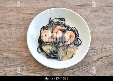 Spaghetti mit schwarzer Tintenfischtinte und Garnelendressing mit weißer Carbonara-Cremesauce auf dem Teller Stockfoto