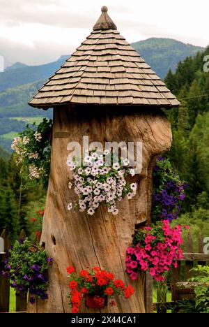 Stamm mit Blumen. Gartendekoration in den Bergen Stockfoto