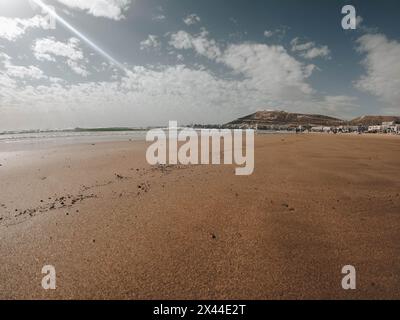Kasbah Agadir Oufella schreibt auf dem Hügel, was bedeutet: Gott, Land, König. Leute, die auf Strandstegen im Sand laufen, Häuser Stockfoto