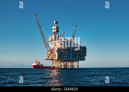 Panoramablick aus nächster Nähe auf die Offshore-Öl- und Gastankplattform, während des Frachtbetriebs mit Versorgungsschiff, während eines schönen Tages im Meer. Stockfoto