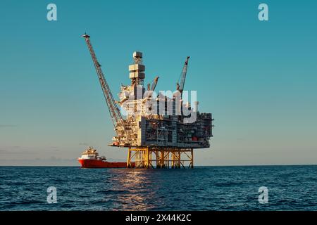 Panoramablick aus nächster Nähe auf die Offshore-Öl- und Gastankplattform, während des Frachtbetriebs mit Versorgungsschiff, während eines schönen Tages im Meer. Stockfoto