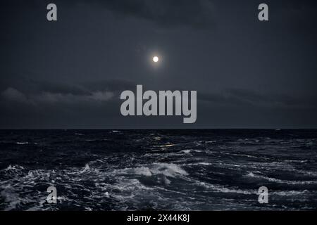 Vollmond am Himmel über dem Meer mit Wellen in der Nacht. Stockfoto