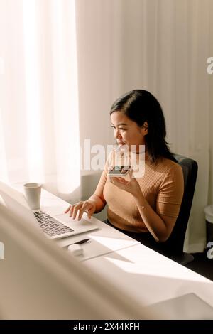 Selbstbewusste Geschäftsfrau, die im Büro über den Lautsprecher des Smartphones telefoniert Stockfoto