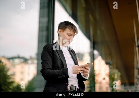 Tiefwinkelansicht einer jungen Geschäftsfrau mit Smartphone gegen Gebäude Stockfoto