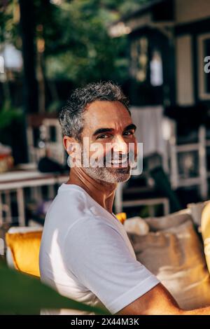 Seitenansicht eines lächelnden, reifen Mannes, der im Wellnessresort sitzt Stockfoto