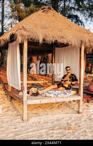 Mann sitzt in Cabana im Urlaub am Strand Stockfoto