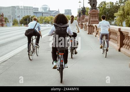 Rückansicht von Geschäftsleuten, die auf einer Brücke in der Stadt durch das Fahrrad pendeln Stockfoto