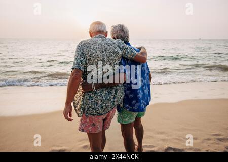 Rückansicht eines schwulen Paares, das mit Armen in Strandnähe steht Stockfoto