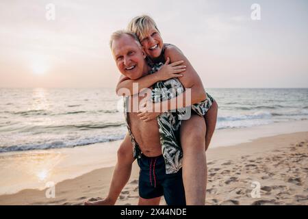 Porträt eines glücklichen älteren Mannes, der ältere Frau im Urlaub am Strand hinterlässt Stockfoto