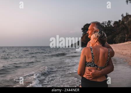 Romantisches Seniorenpaar, das während des Urlaubs auf das Meer am Strand blickt Stockfoto