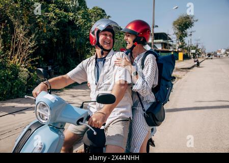 Glücklicher Senior-Mann, der einen Roadtrip mit einer Frau auf dem Roller genießt Stockfoto