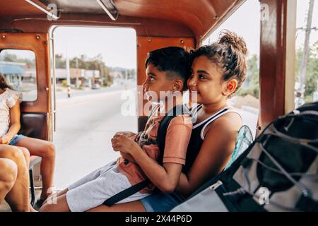 Junge, der auf dem Schoß seiner Schwester sitzt, während er im Urlaub vom Tuk-Tuk reist Stockfoto