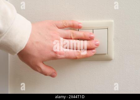 Die Hand einer Frau schaltet das Licht mit einem elektrischen Schalter an, Nahaufnahme Stockfoto