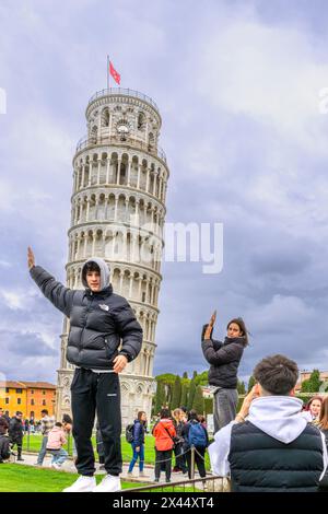 Touristen, die so aussehen wollen, als würden sie den Schiefen Turm von Pisa (Torre di Pisa) stützen. Der Turm ist die beliebteste Sehenswürdigkeit in Pisa. Stockfoto