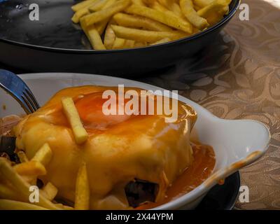 Das Francesinha, ein Sandwich aus Porto, Portugal, mit Schweinefleisch, geräucherter Wurst, Speck, Rindfleisch und einem Spiegelei, bedeckt mit einer käsigen Sauce Stockfoto