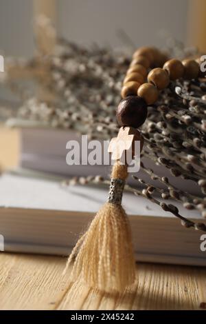 Rosenkranzperlen, Bücher und Weidenzweige auf dem Tisch, Nahaufnahme Stockfoto