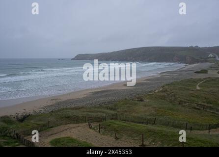 Wunderschöne Landschaften in Frankreich, Bretagne. Baie des Trepasses Beach in Plogoff. Surfer und alter Leuchtturm (Phare de la Vieille). Bewölkter Frühlingstag. Se Stockfoto