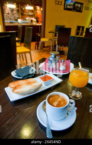 Spanisches Frühstück: Toast mit Olivenöl und Tomaten, Orangensaft und einer Tasse Kaffee. Stockfoto