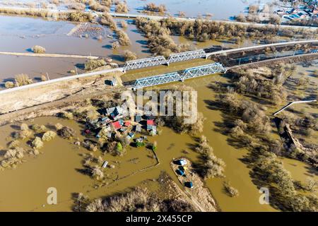 Starke Flut auf dem Land, Blick von der Vogelperspektive auf eine Eisenbahnbrücke und einen kleinen Bauernhof Stockfoto