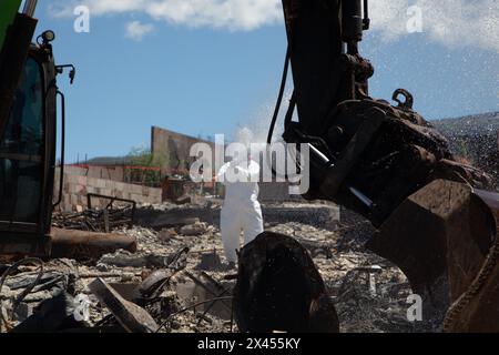 Maui, Usa. 18. April 2024. U. Die Vertragsarbeiter des US Army Corps of Engineer sprühen Wasser, um den Staub während der Säuberungs- und Beseitigungsarbeiten nach den Waldbränden zu reduzieren, die am 18. April 2024 in Maui, Hawaii, das historische Dorf Lahaina heimsuchten. Die Brände am 8. August 2023 zerstörten 80 % der Stadt und töteten über 100 Menschen. Quelle: Makenzie Leonard/USACE/Alamy Live News Stockfoto