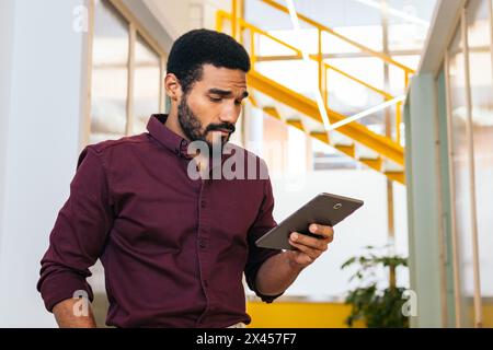 Gutaussehender Mann im Hemd, der mit einem Tablet in einer Coworking arbeitet Stockfoto