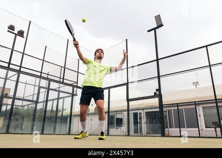 Junger Mann, der Paddle-Tennis spielt Stockfoto