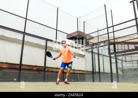 Junger Mann, der Paddle-Tennis spielt Stockfoto