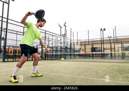 Junger Mann, der in einem Paddle-Tennis-Spiel dient Stockfoto