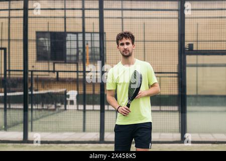 Junger Mann spielt Paddle-Tennis auf einem grünen Platz Stockfoto