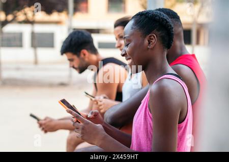 Gruppe multirassischer Freunde, die nach einem Basketballspiel ein Smartphone verwenden Stockfoto