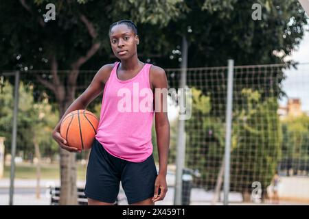 Porträt einer afroamerikanischen Basketballspielerin, die selbstbewusst einen Basketball hält Stockfoto