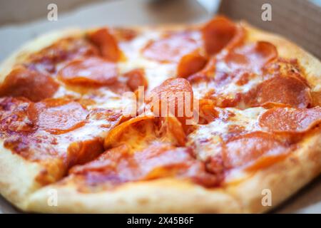 Eine Pepperoni-Pizza, ein Grundnahrungsmittel in der Fast-Food-Küche, liegt in einem Karton. Dieses Backwarengericht ist ein klassisches Rezept für kalifornische Pizza Stockfoto