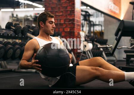 Junger Mann, der in einem Fitnessstudio Gewichtskugeln macht Stockfoto
